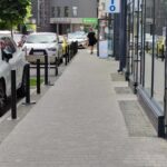 a row of parked cars sitting next to a sidewalk