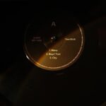 A vinyl record spinning on a turntable in low light.